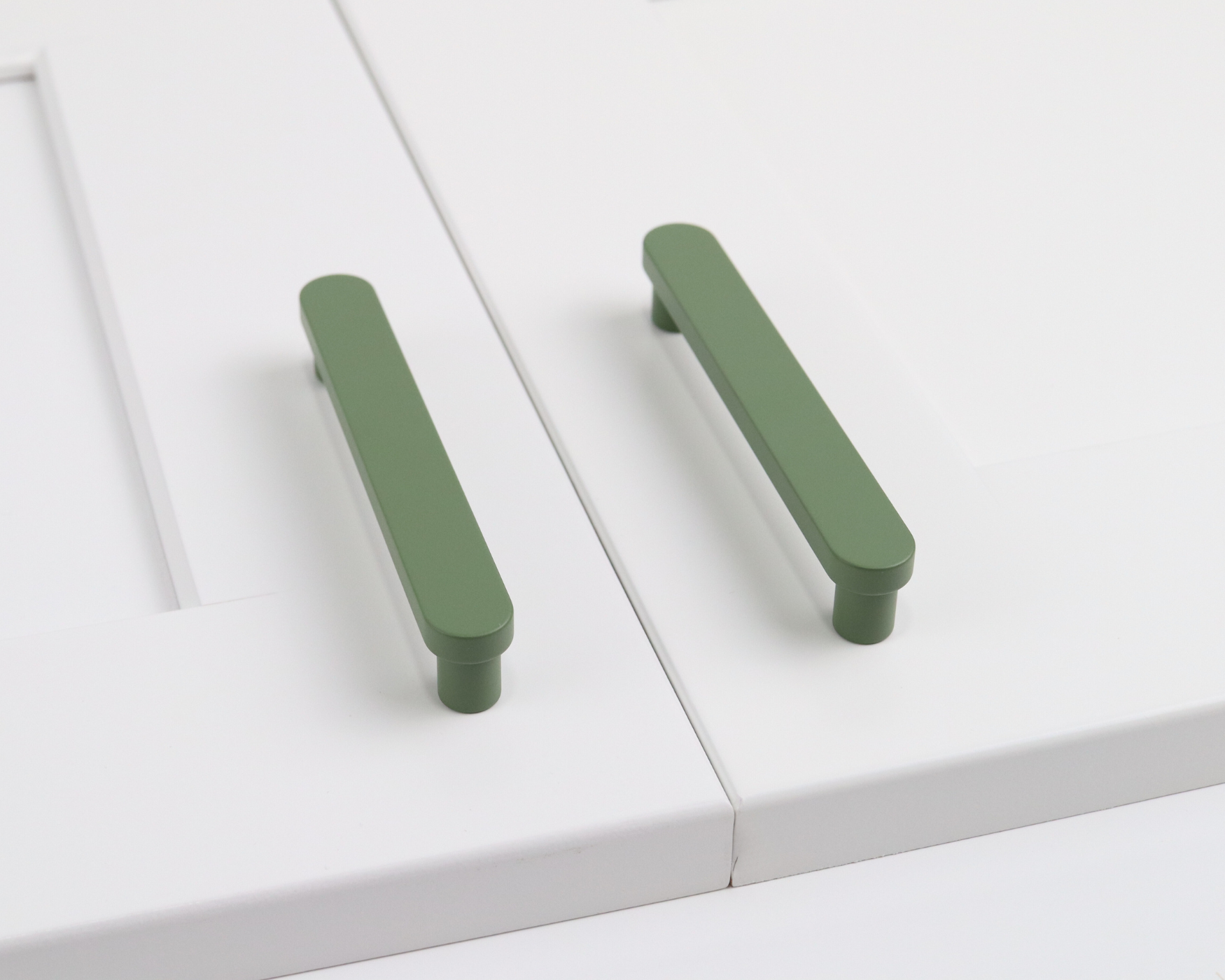 White kitchen cabinet doors with green handles, showcasing a simple, modern design that adds a touch of color and style.