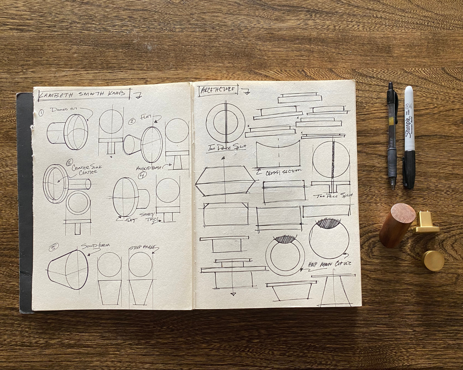 Sketchbook showing original hardware knob designs and construction diagrams on a wooden table with pens and sample knobs.
