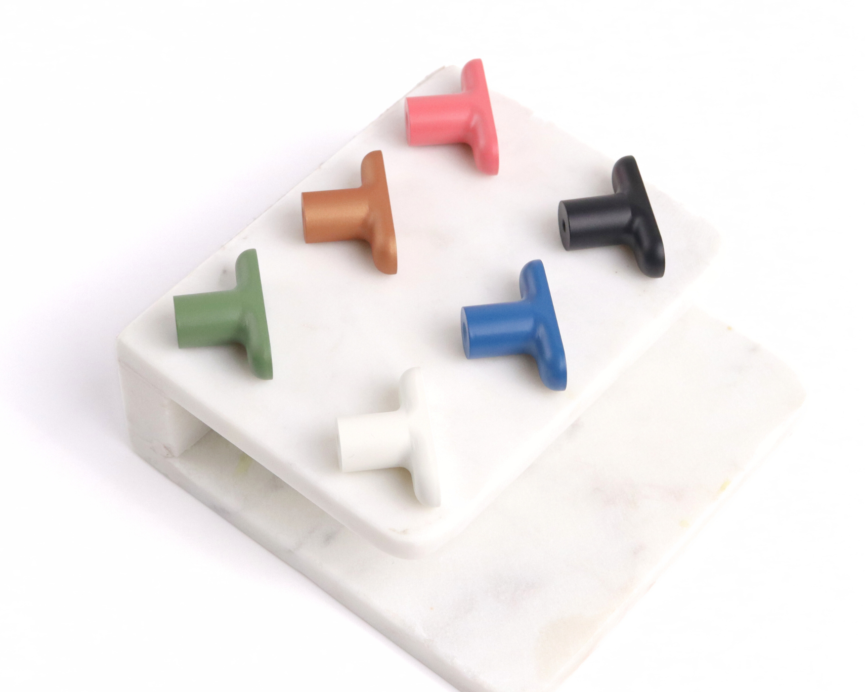 Assorted Mid Century Modern T-Bar Knobs in six colors displayed on stacked marble slabs.