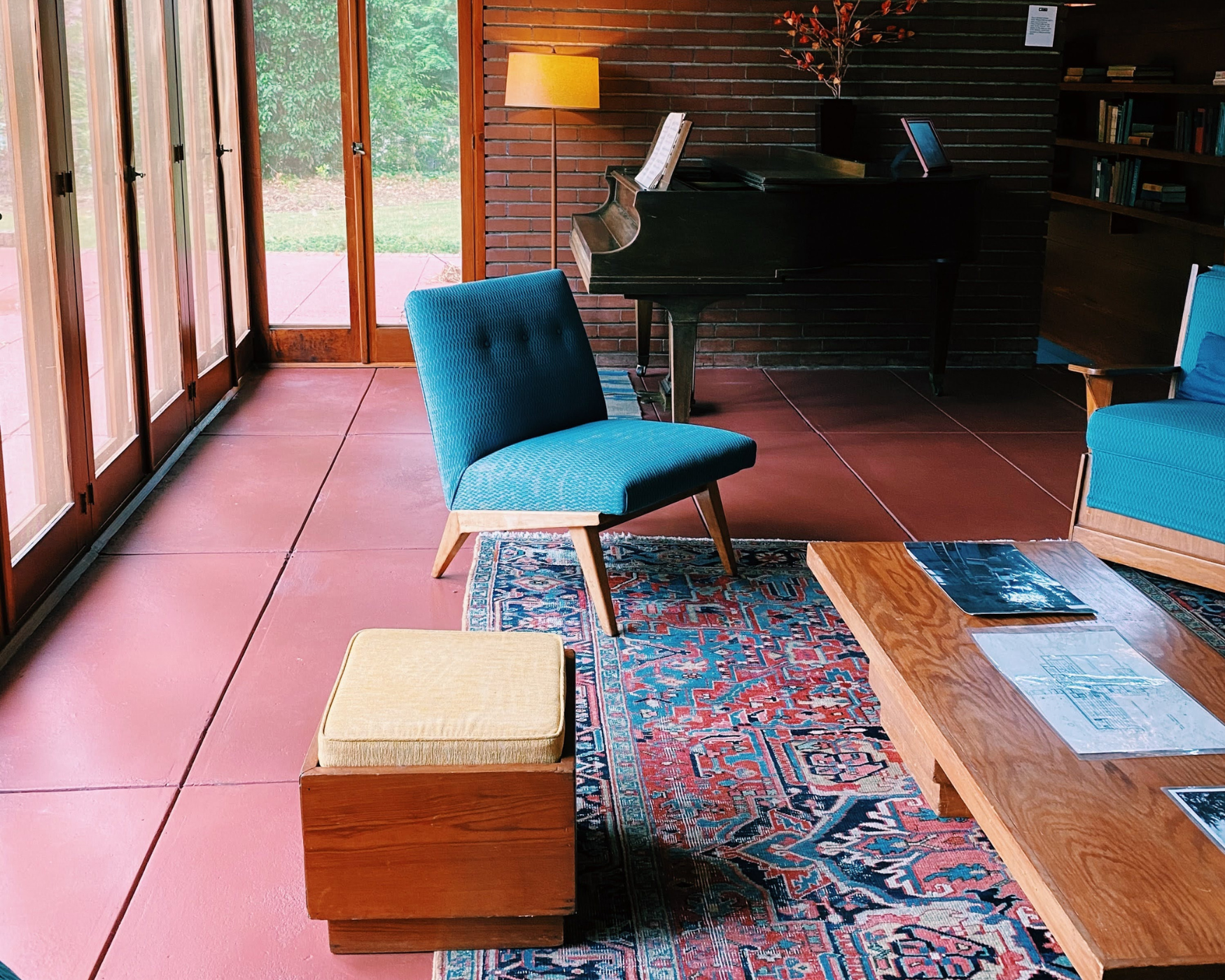A cozy Mid-Century Modern living room featuring iconic furniture such as a blue chair, wooden coffee table, and patterned rug