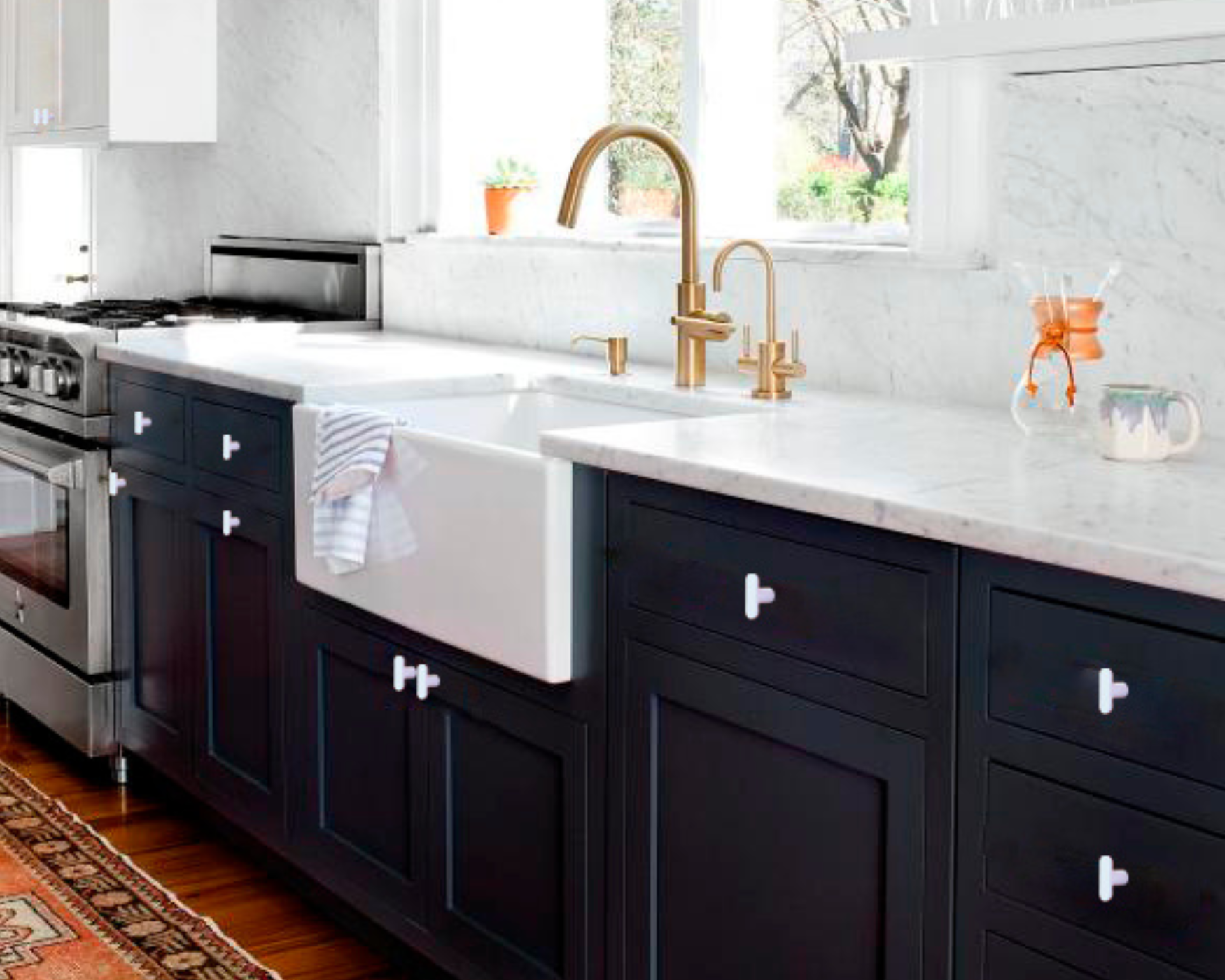 Modern kitchen with brass faucet, farmhouse sink, and matte black cabinets featuring white t bar knobs.