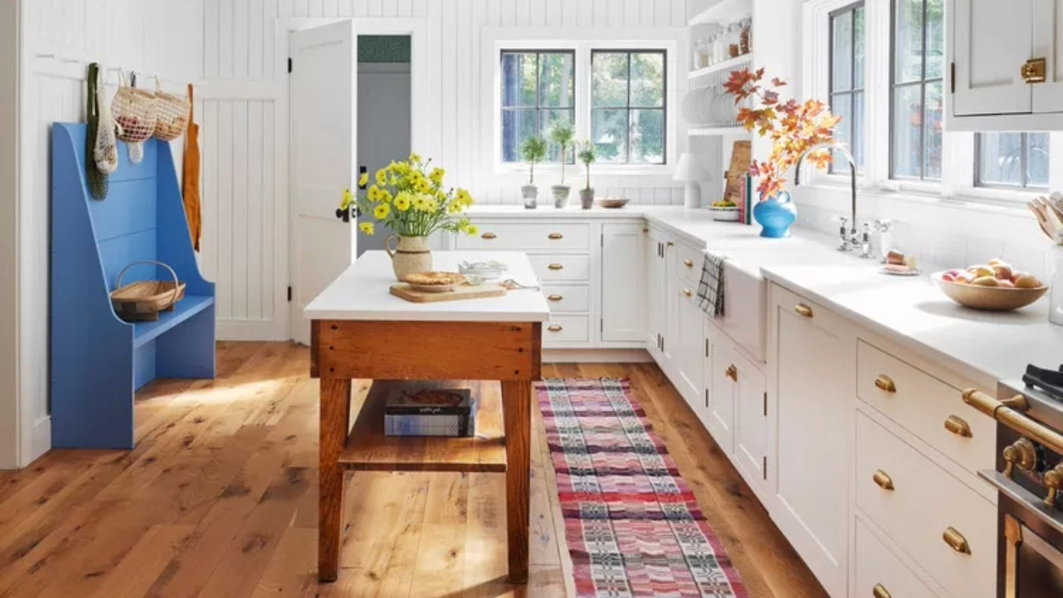A white kitchen with copper hardware and a beautiful wooden island in the center.