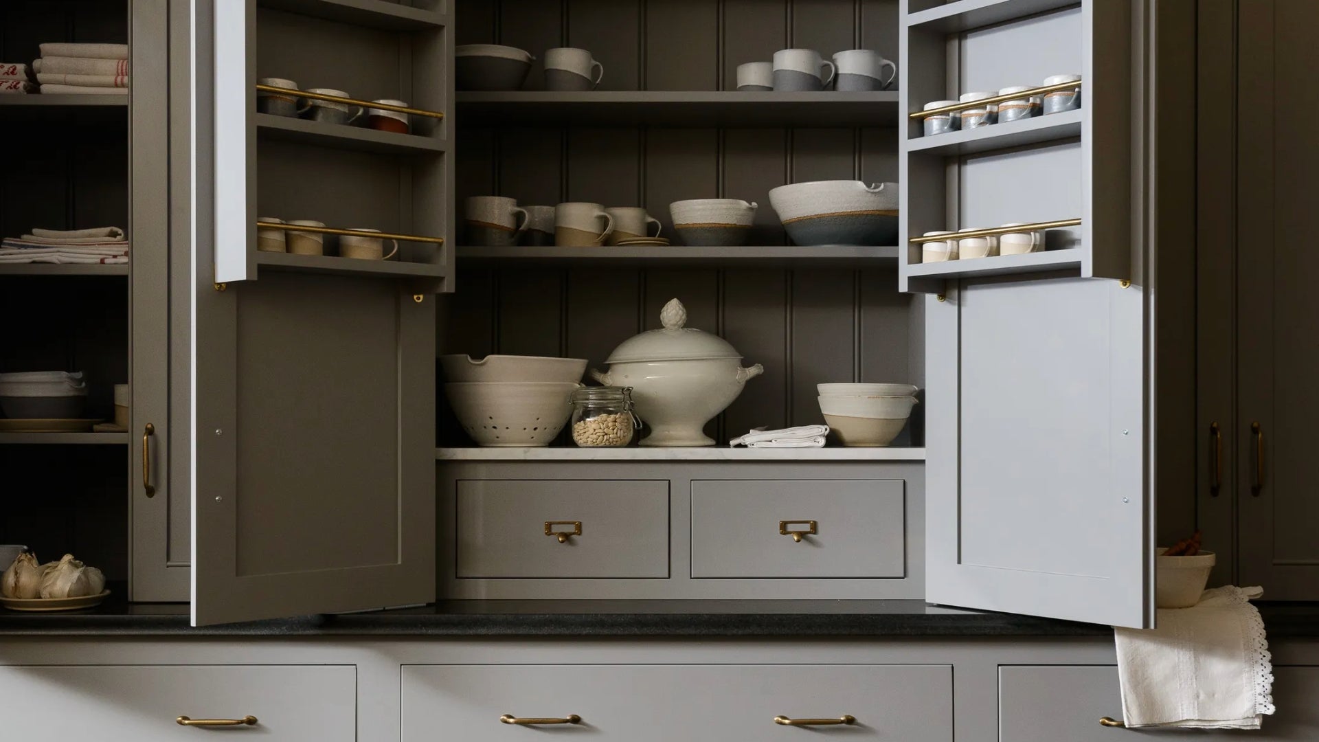 Architectural Digest image of beautiful gray cabinetry with plates and cups displayed.