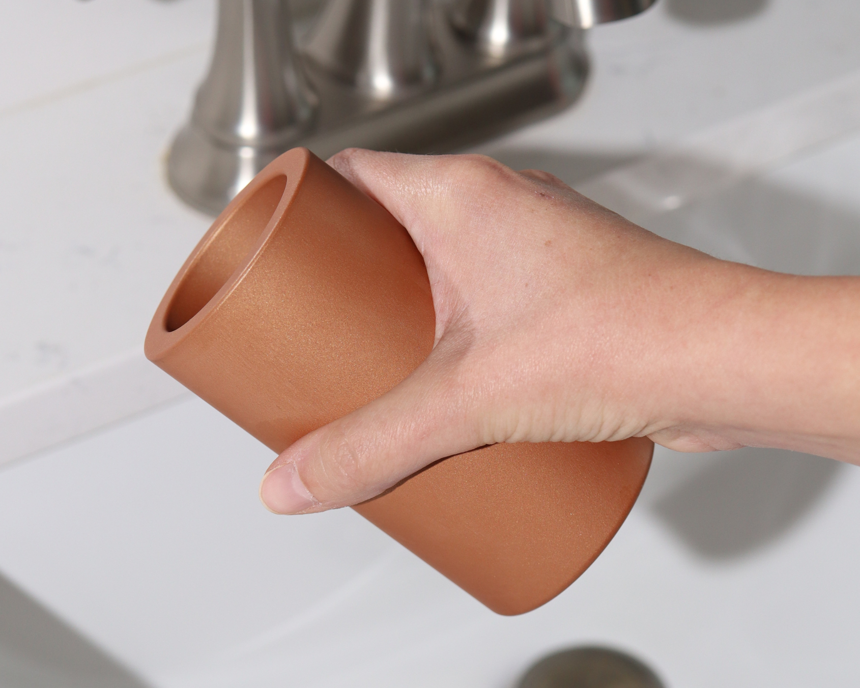 Hand holding a modern bathroom organizer over a sink, showcasing a stylish, functional upgrade for bathroom accessories.