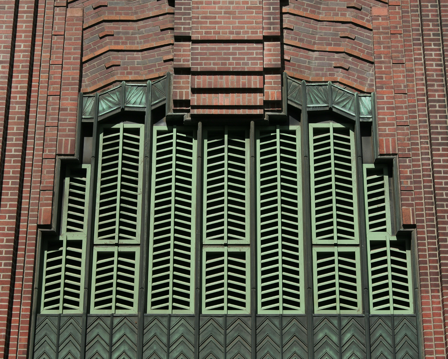 Art Deco architecture with geometric patterns and a green metal grille, showcasing timeless elegance and sophisticated design.