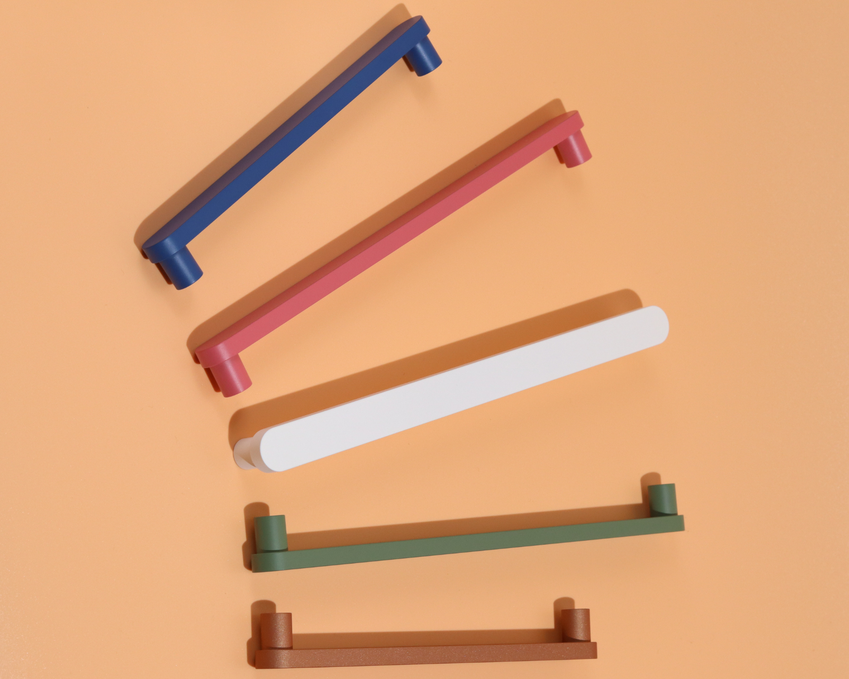 Colorful cabinet handles in rose, polo, snow, olive, and copper on peach background in a modern, mid-century style