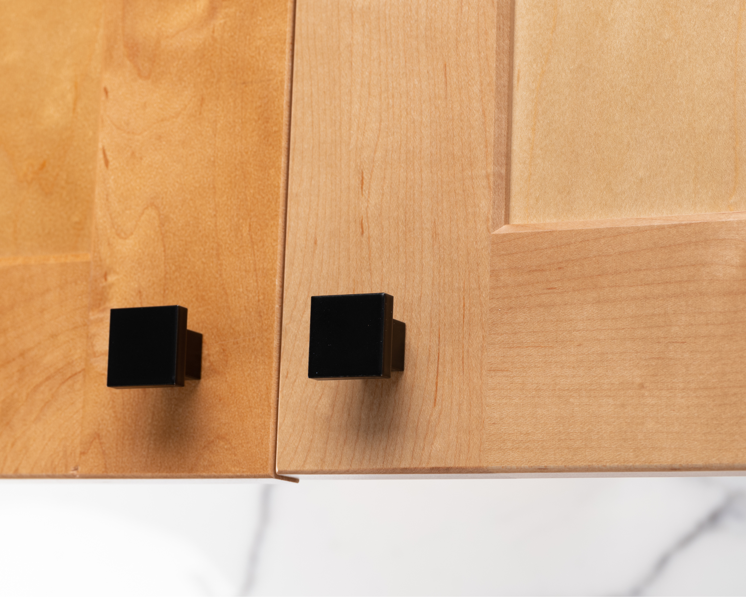 Black Art Deco square knobs on natural wood cabinet doors, showcasing geometric symmetry and modern luxury.